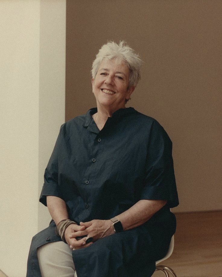 An older woman seated, smiling